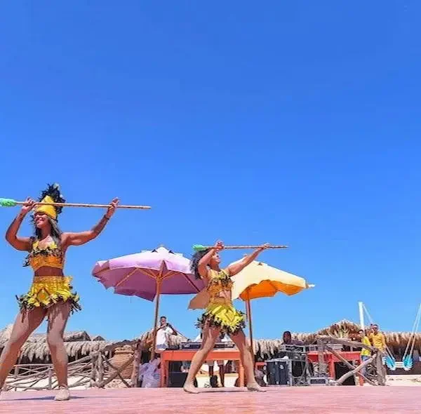 Professional dancers in yellow tropical costumes performing an animation show on a stage at Paradise Island Hurghada