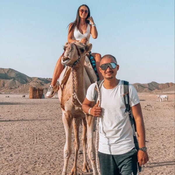 Quad 3 Hours Safari Hurghada featuring a woman riding a camel while her partner leads the way in the desert