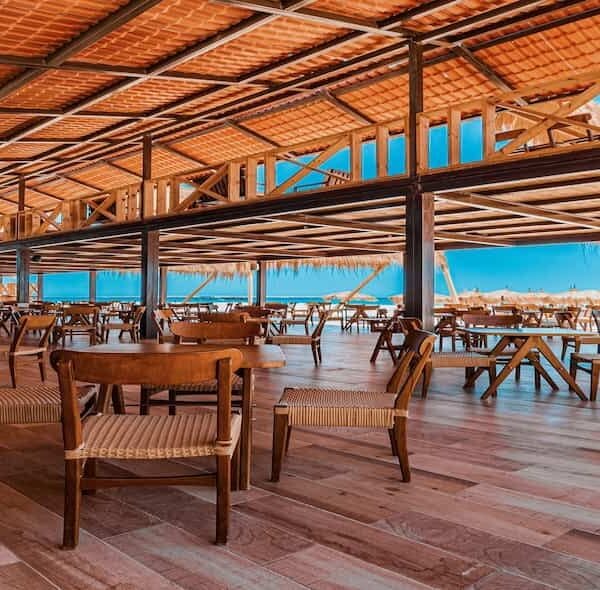 A spacious, shaded seating area on a tourist boat in Egypt, featuring wooden architecture and a panoramic view of the clear blue sea