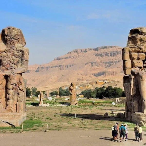 Two massive stone statues of Pharaoh Amenhotep III seated on thrones, located in the Theban Necropolis on the West Bank of Luxor.