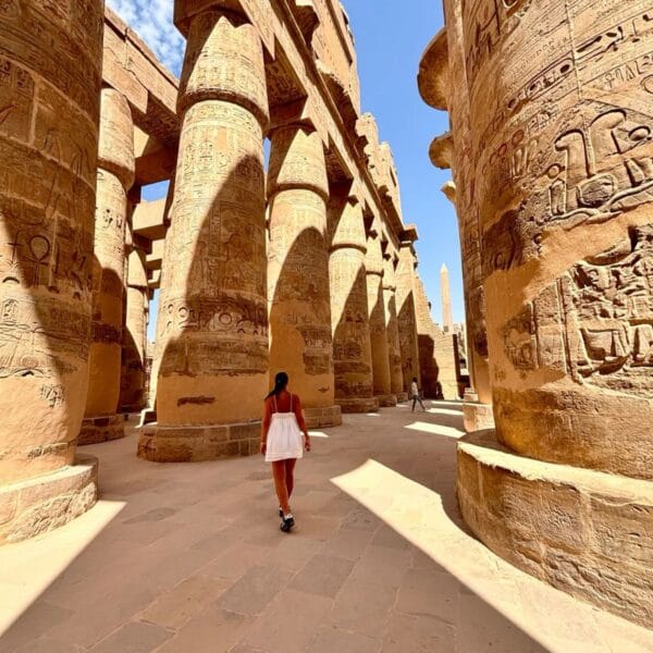 Luxor Over Day: A tourist walking through the Great Hypostyle Hall of Karnak Temple, surrounded by massive ancient Egyptian columns with hieroglyphs