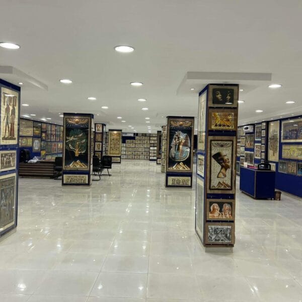 A wide view of a spacious gallery in the Papyrus Museum during a Luxor trip, displaying traditional Egyptian paintings and pharaonic art on papyrus.