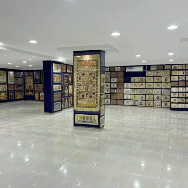 A bright museum room in Luxor showcasing various papyrus artworks, including depictions of Egyptian cats, goddesses, and royal symbols.