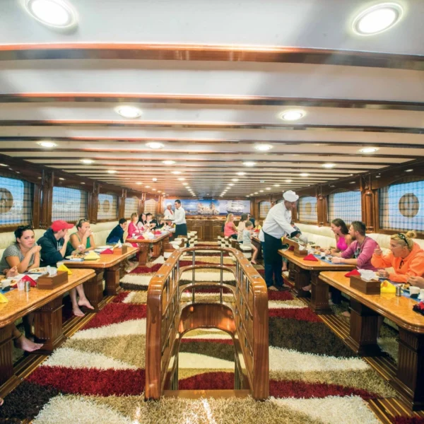 Tourists having lunch inside a luxurious and spacious restaurant lounge on board a tourist yacht.
