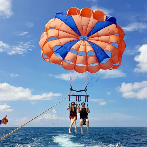 Parasailing Hurghada: A tandem parasailing flight with an orange and blue parachute over the deep blue sea, capturing a fun holiday moment