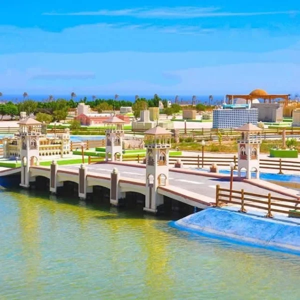 A miniature replica of Stanley Bridge in Alexandria, featuring its iconic four towers over a blue waterway at Mini Egypt Park