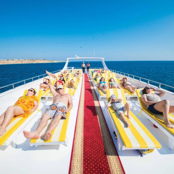 Tourists lie on yellow sun loungers on the yacht's sun deck under the sun and blue sky